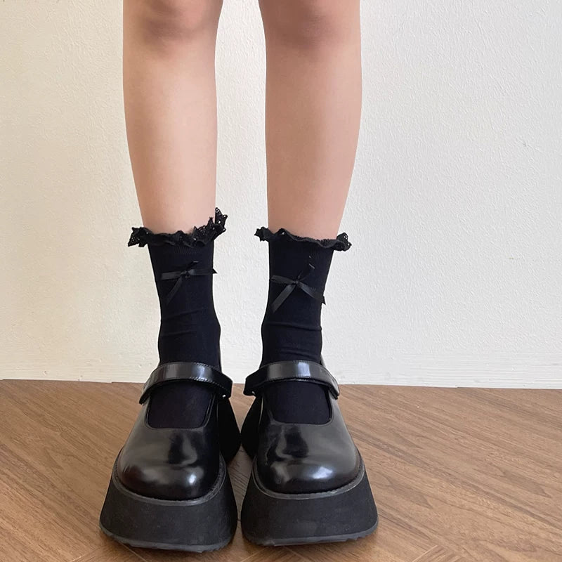 White lace-trimmed socks with ribbon bows styled with black loafers.
