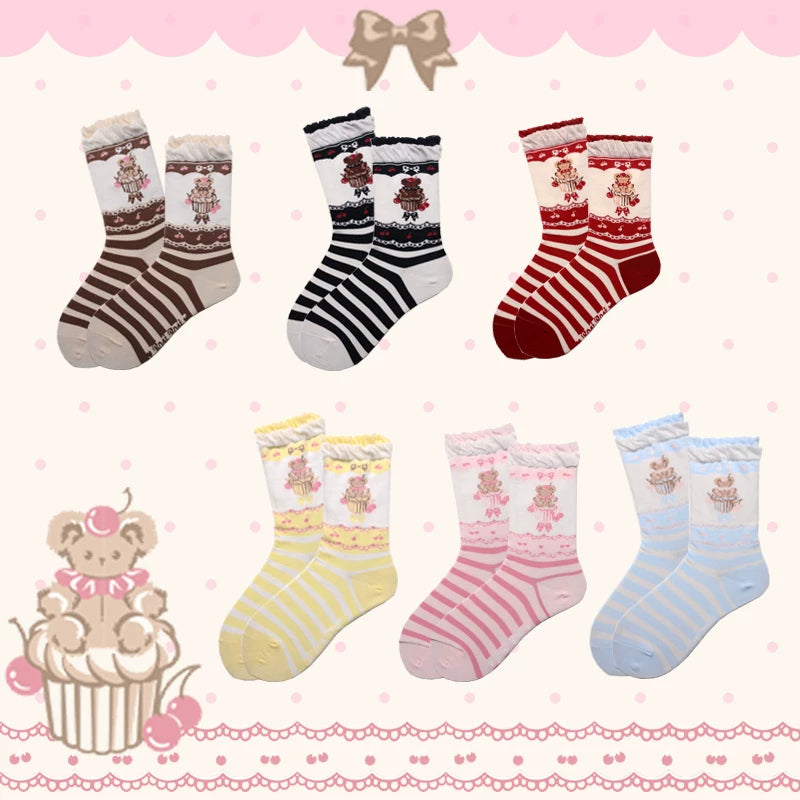 Pink, blue, and yellow mid-calf socks with bear cupcake motifs arranged on a pastel garment.