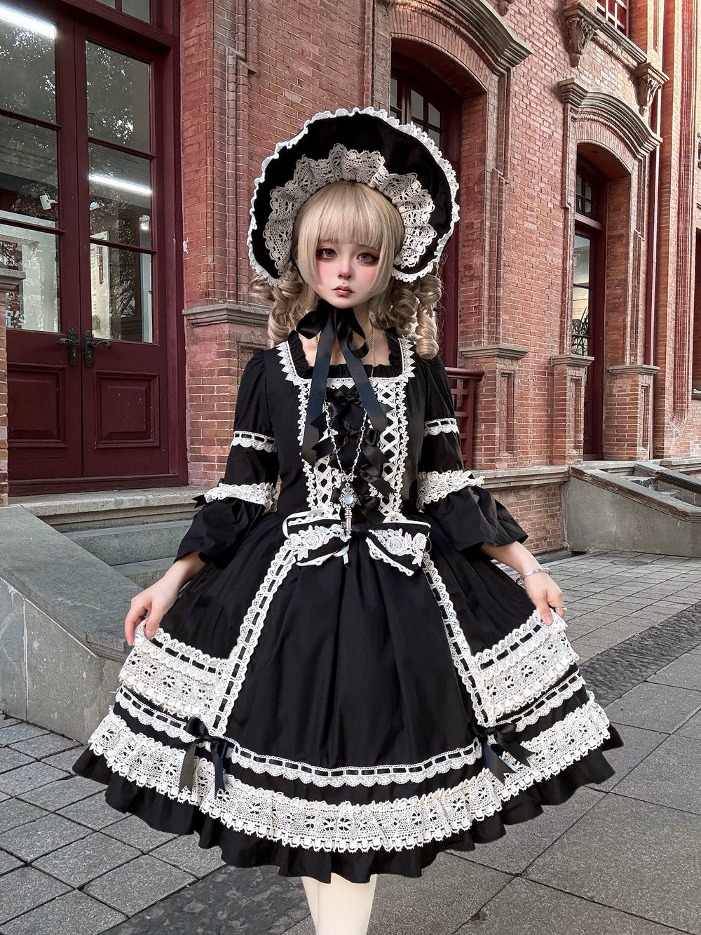 Model wearing a black OP dress with white lace trim, ribbon lacing and a tiered skirt.