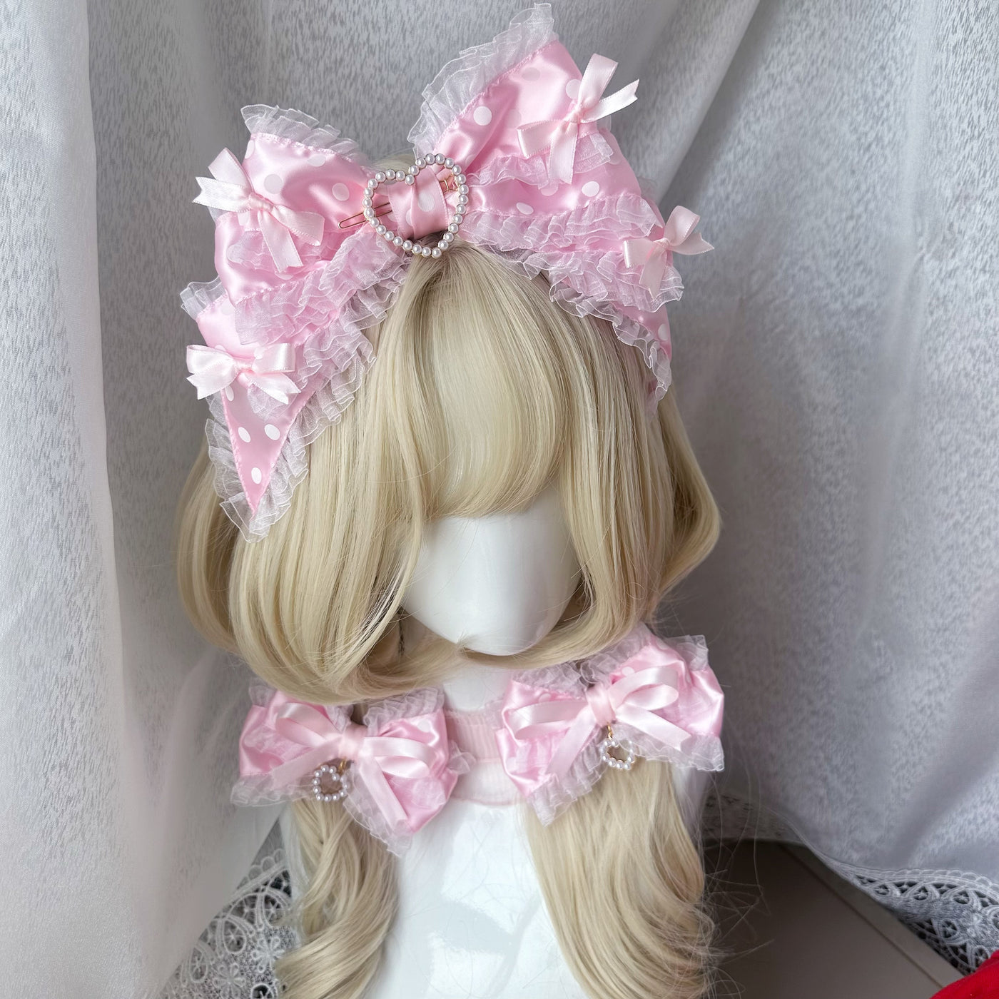 Pink polka-dot bow headband with pearl-edged heart detail on blonde hair.