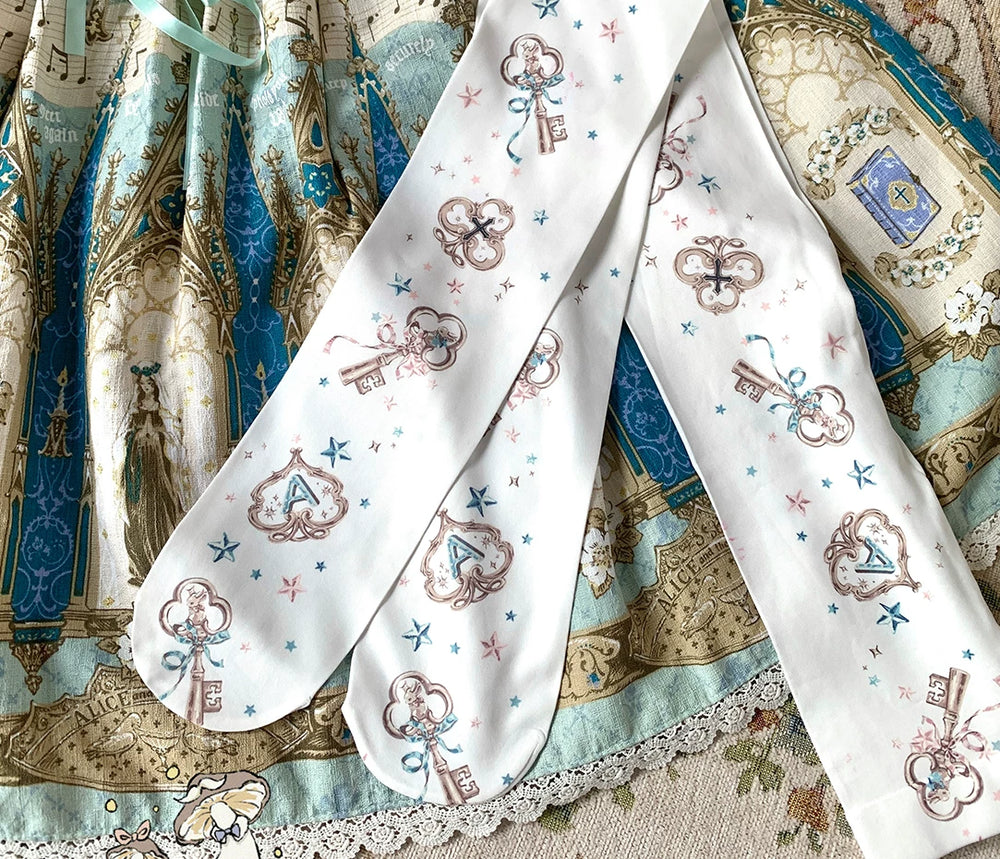 White printed tights with key, letter and star motifs laid over blue patterned fabric.