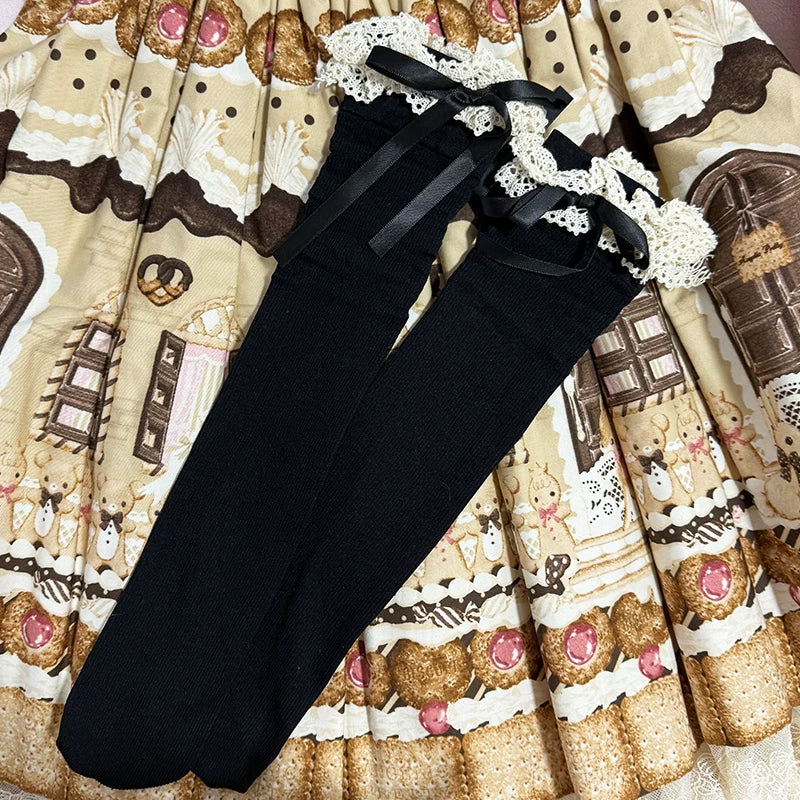 Black ribbed calf socks with lace cuffs and black ribbon bows on a patterned fabric background.