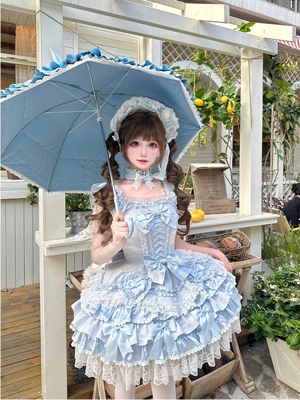 Blue ruffled Lolita dress with a train, six bows, and heart brooches shown in outdoor styling.