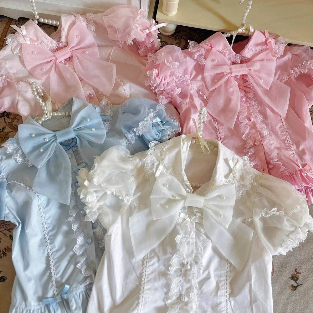 Pastel lace-trimmed blouses with large bows arranged together.