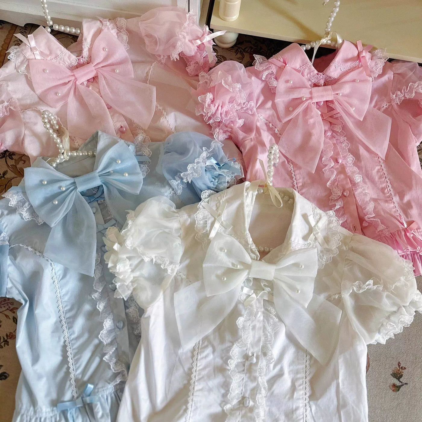Pastel lace-trimmed blouses with large bows arranged together.