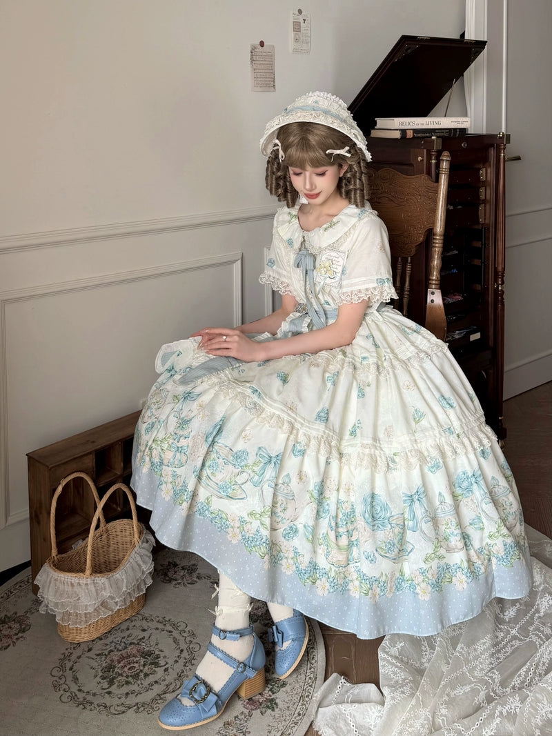 Close-up of the dress's floral tea-set print, lace trim, and center front cameo pendant