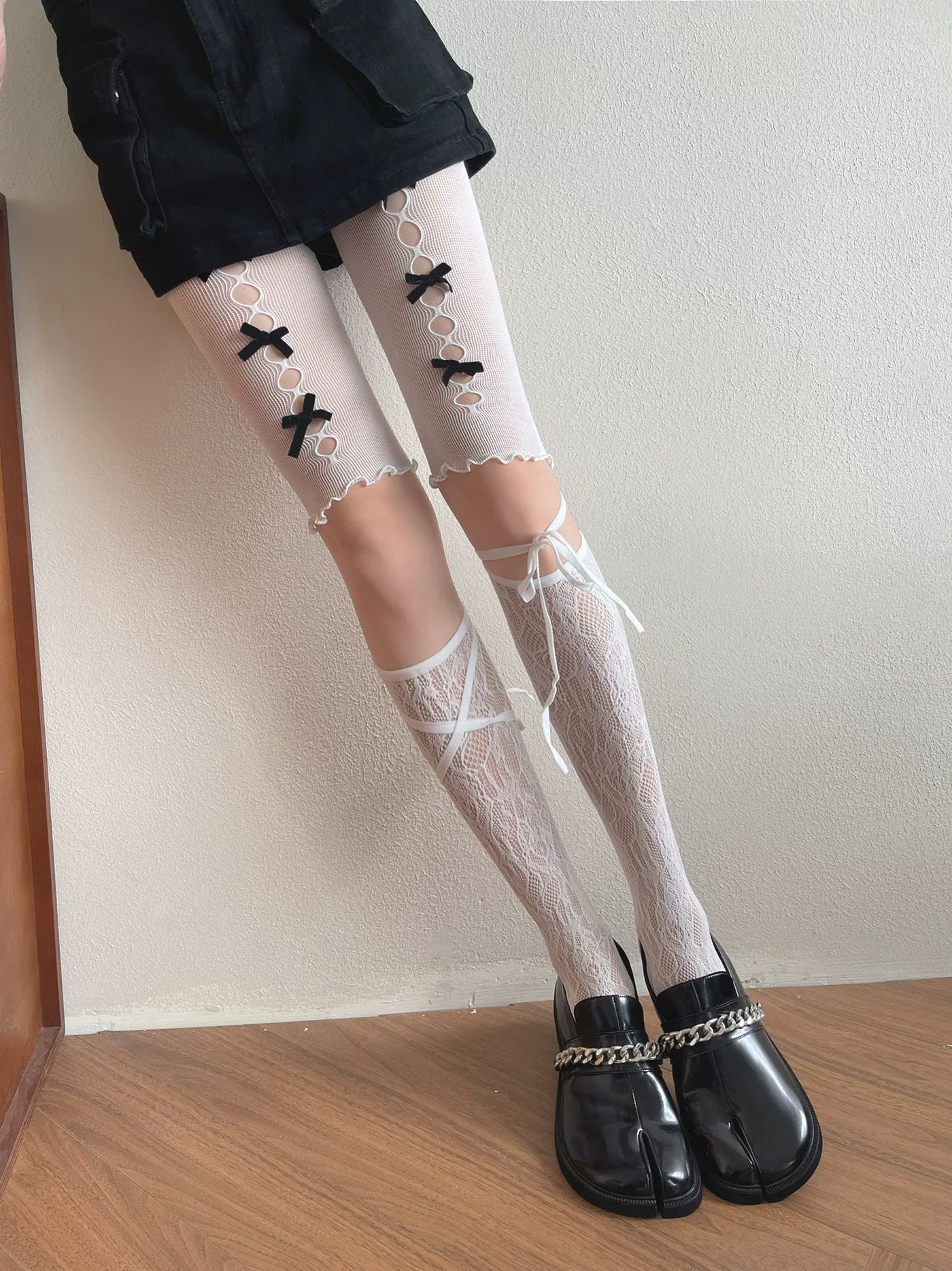 White cutout lace legwear with black bows and ribbon straps