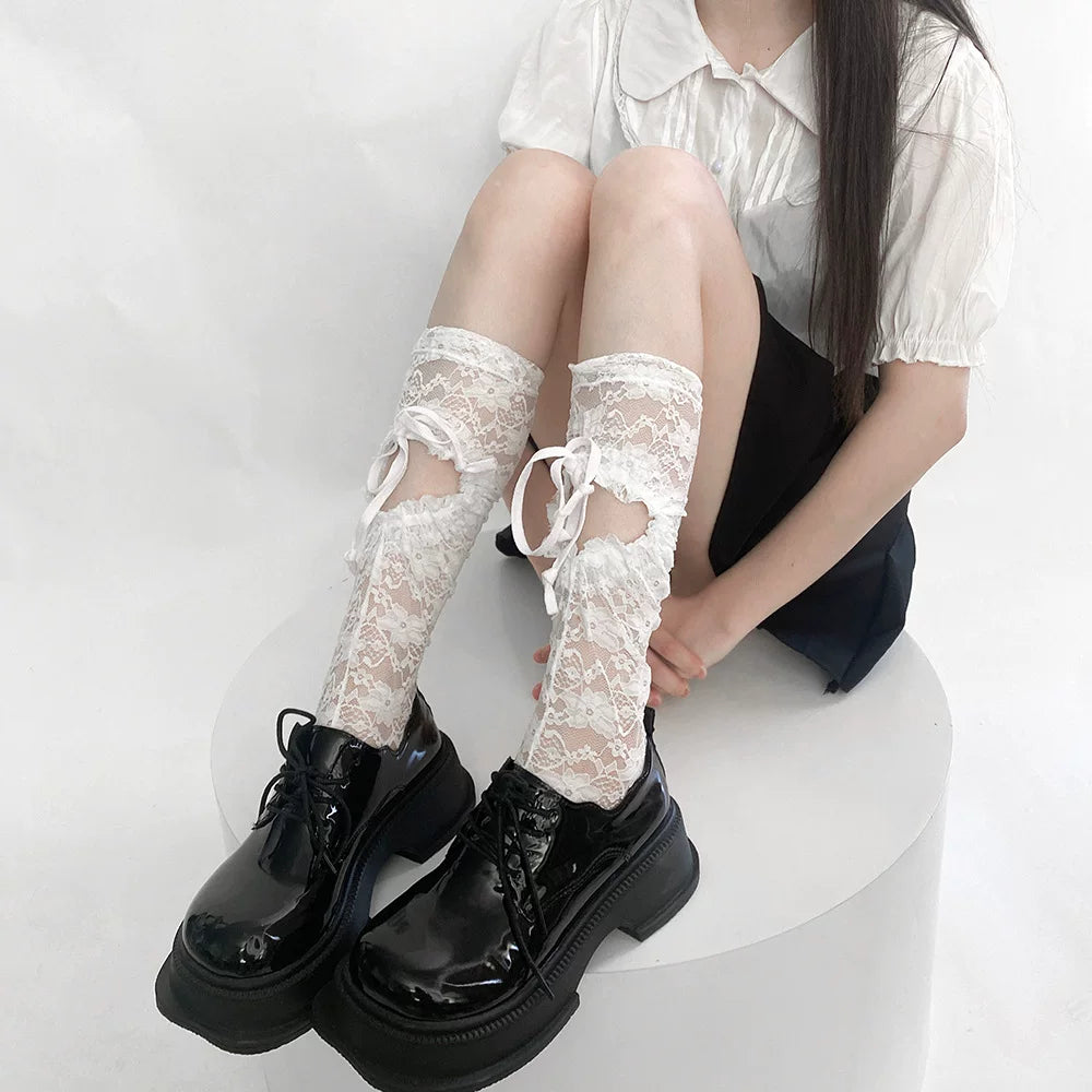 Model wearing white lace mid-calf socks with ribbon lacing and black platform shoes.