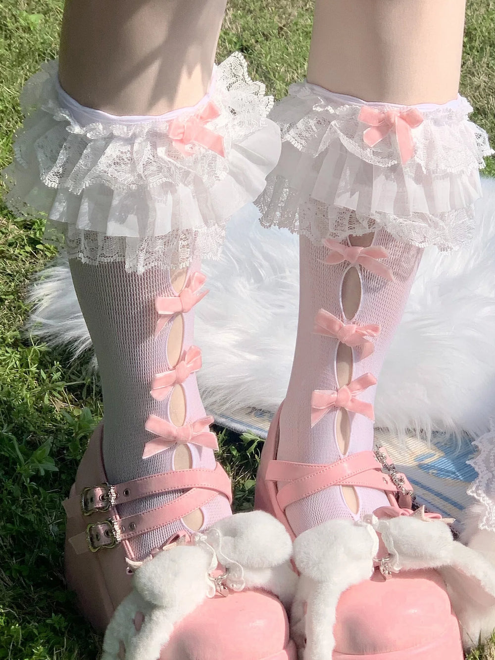 Model wearing white cutout short socks with black bows, lace cuffs, and black patent shoes.