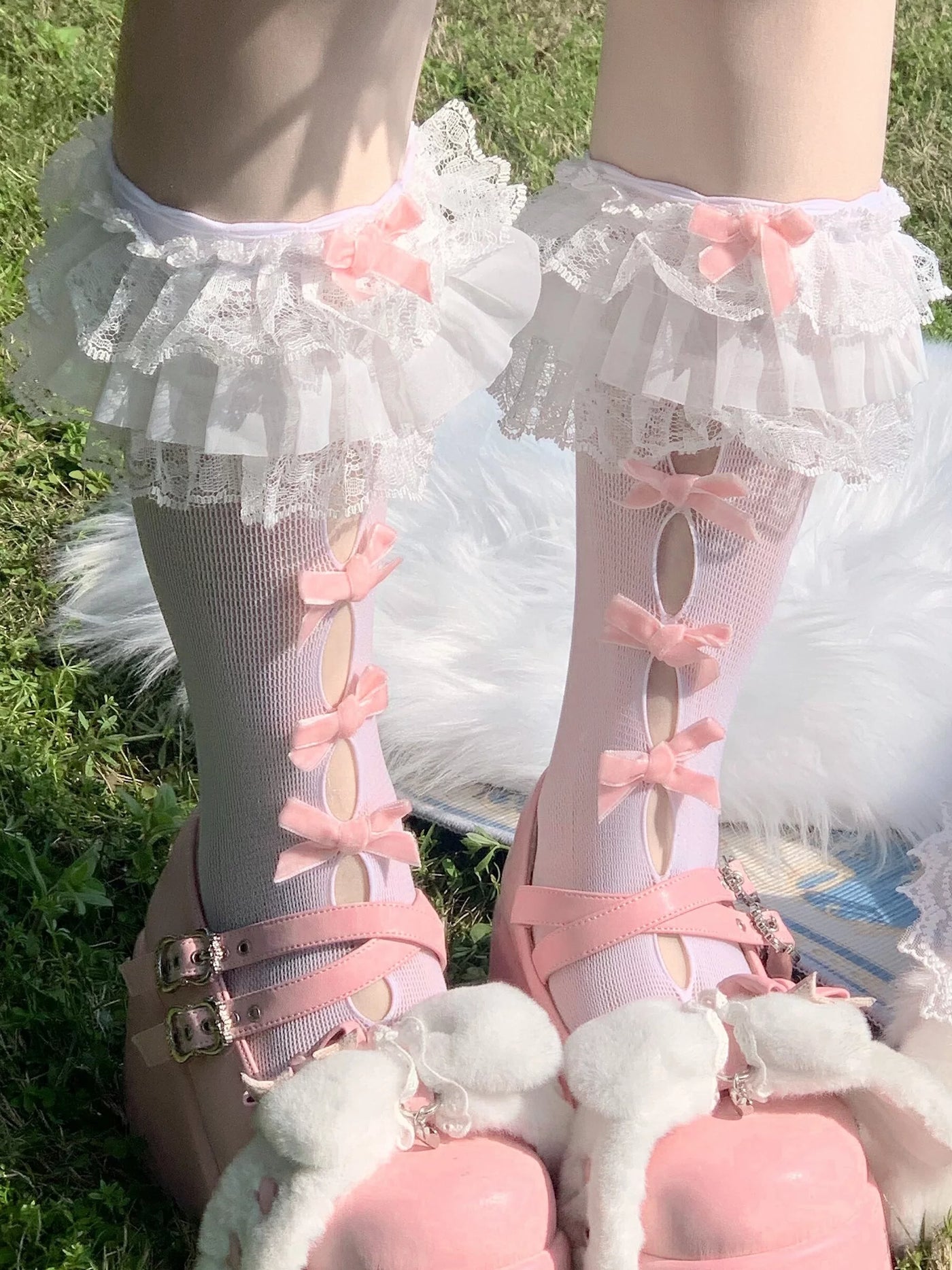 Model wearing white cutout short socks with black bows, lace cuffs, and black patent shoes.