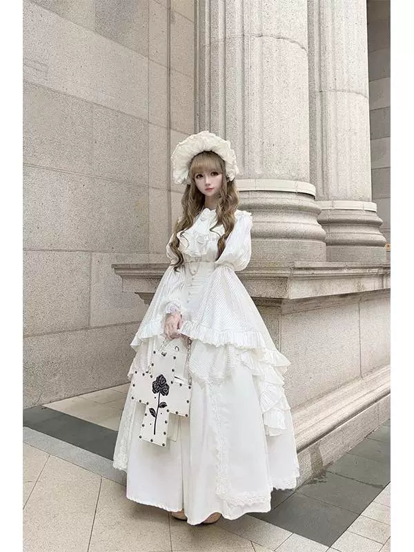 White blouse set with ruffled princess sleeves, fishbone half-skirt, and bib worn by a model.