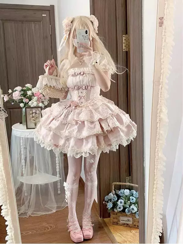 Pink JSK dress with layered ruffles, lace trim and ribbon details shown in a mirror.