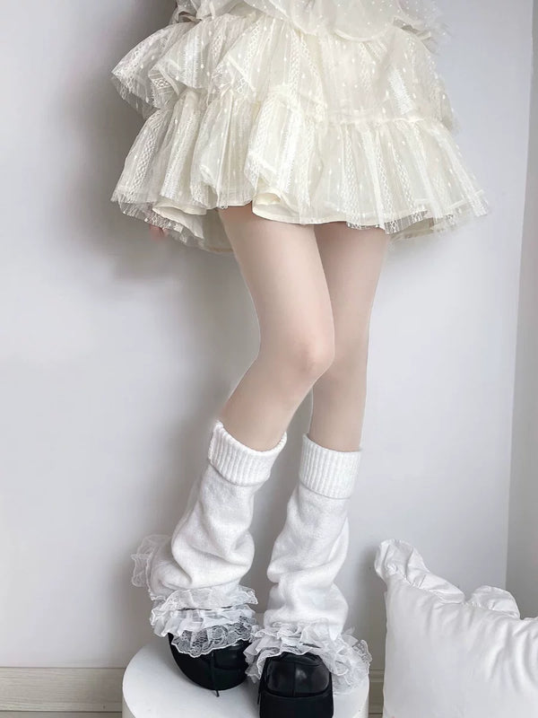 White rib-knit leg warmers with flared lace cuffs worn with black platform shoes.