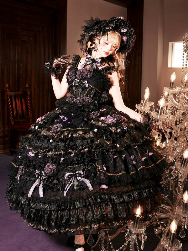 Model wearing a black-purple Gothic Lolita jumper skirt with purple flowers and butterfly motifs beside a crystal chandelier.