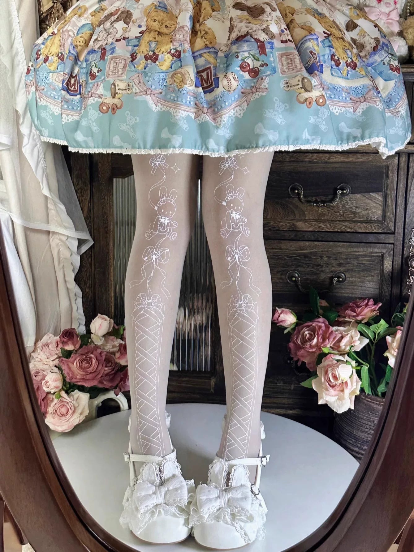 White tights with outlined rabbit, bow, and gift motifs shown beneath a printed skirt