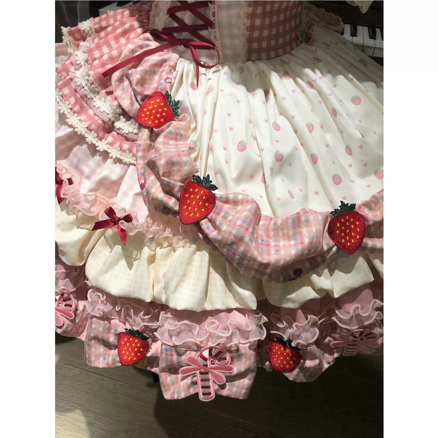 Pink strawberry and gingham Lolita OP dress with layered ruffles on a mannequin