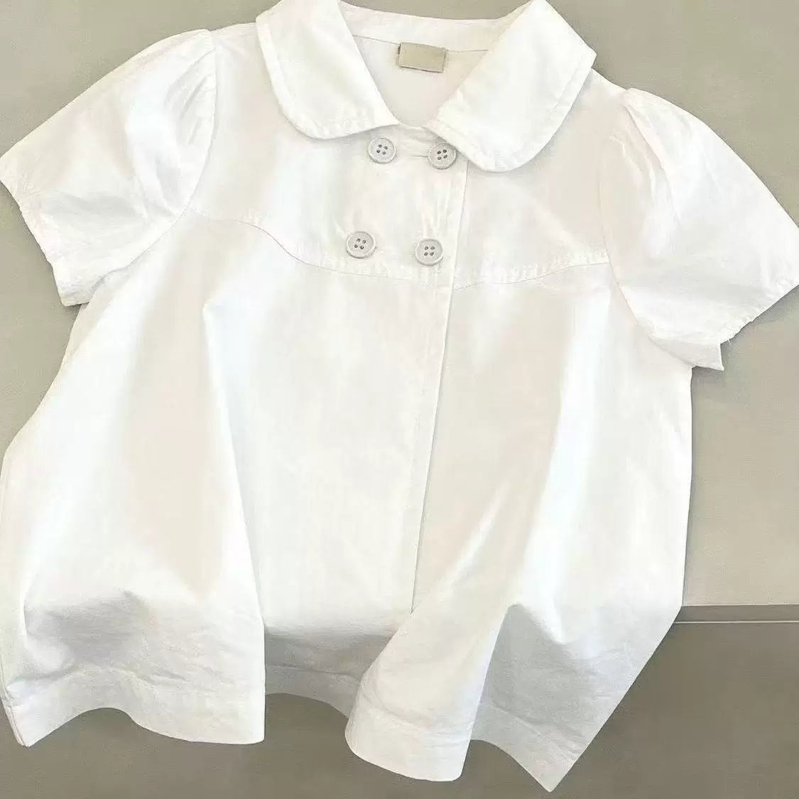 White short-sleeve blouse with rounded collar and double-breasted front