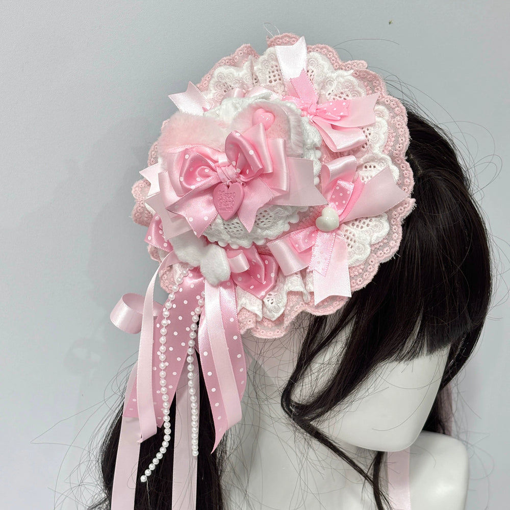 Pink cat-ear small top hat with lace and bows on a dark-haired mannequin.
