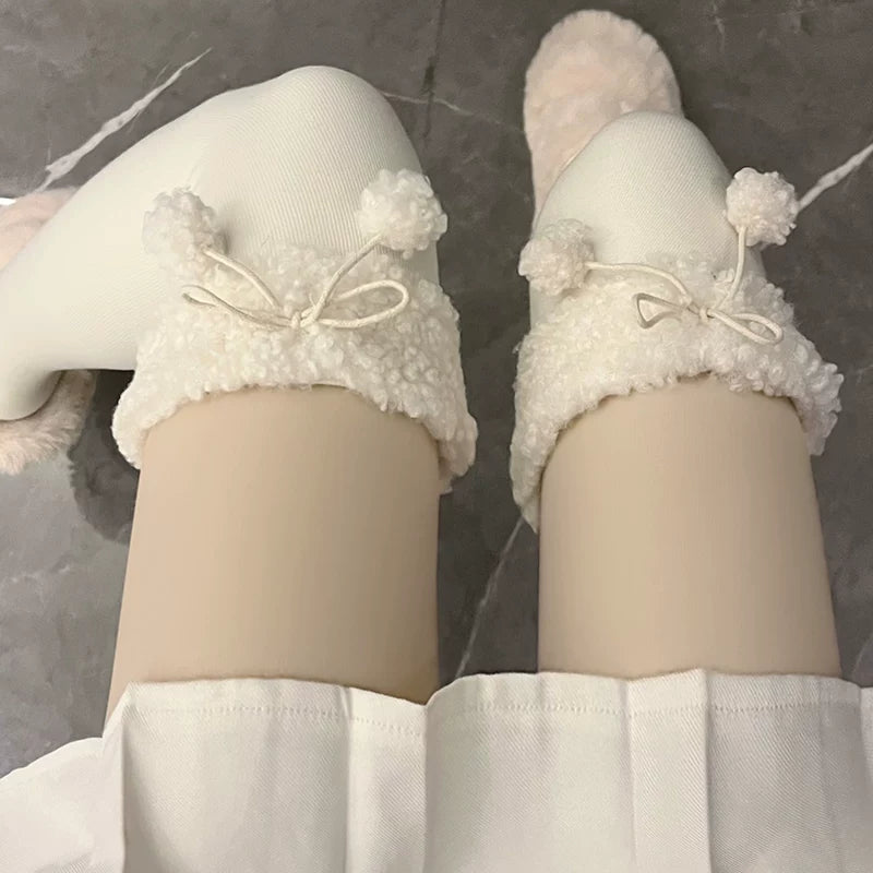 Milky white over-the-knee socks with fleece trim and pom-pom ties styled with a cream outfit.