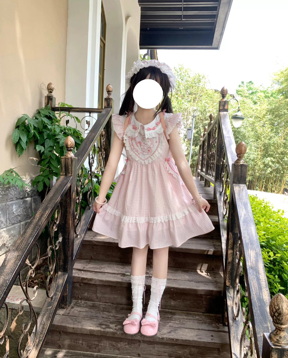 Pink gingham Lolita OP dress with flutter sleeves and a ruffled bib worn outdoors.