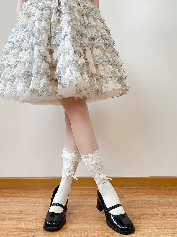 White mid-calf lace socks with ruffled edges and ribbon bows, worn with black strap shoes.