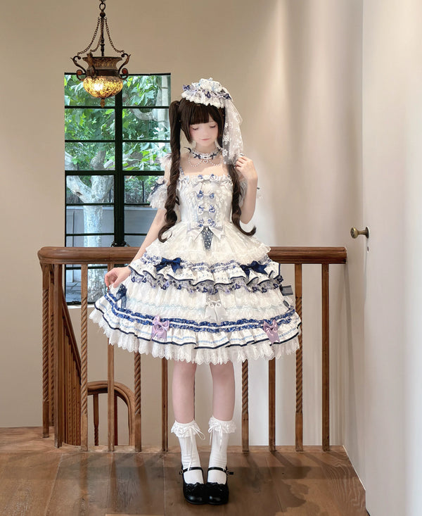 Blue-and-white OP dress with layered lace, bows and floral trim, styled with blue flowers.