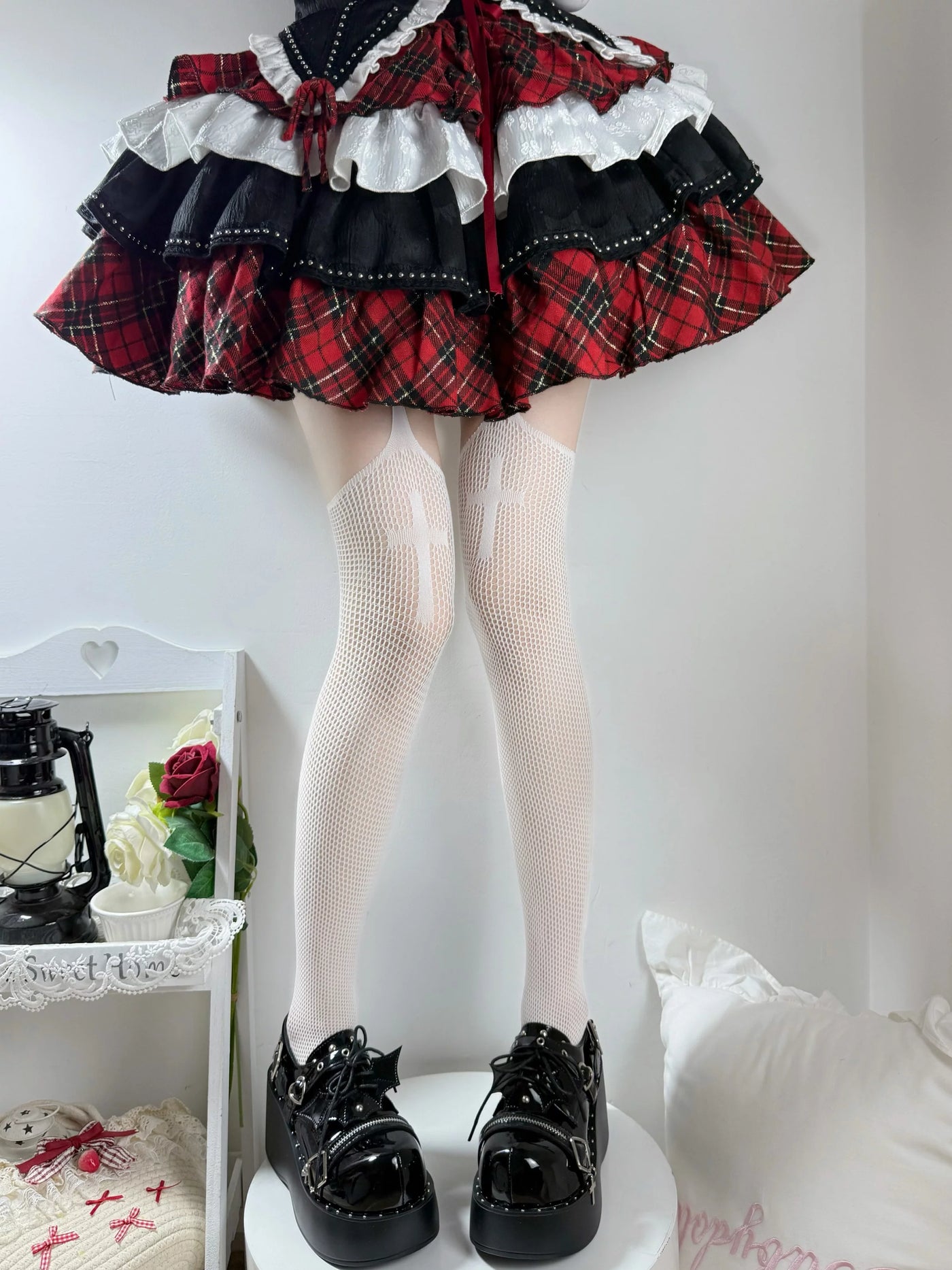 Lower-body styling image showing cross-motif fishnet hosiery with black sock covers.
