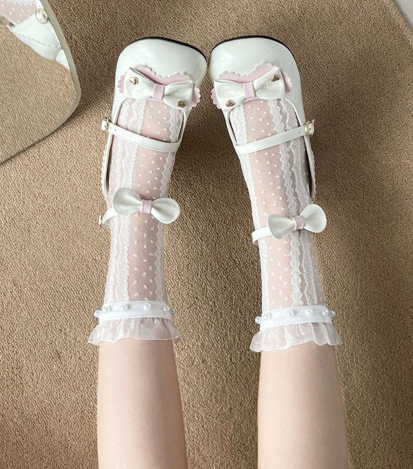 White dotted mesh socks with lace panels, pearl trim, and bows worn with white Mary Jane shoes.