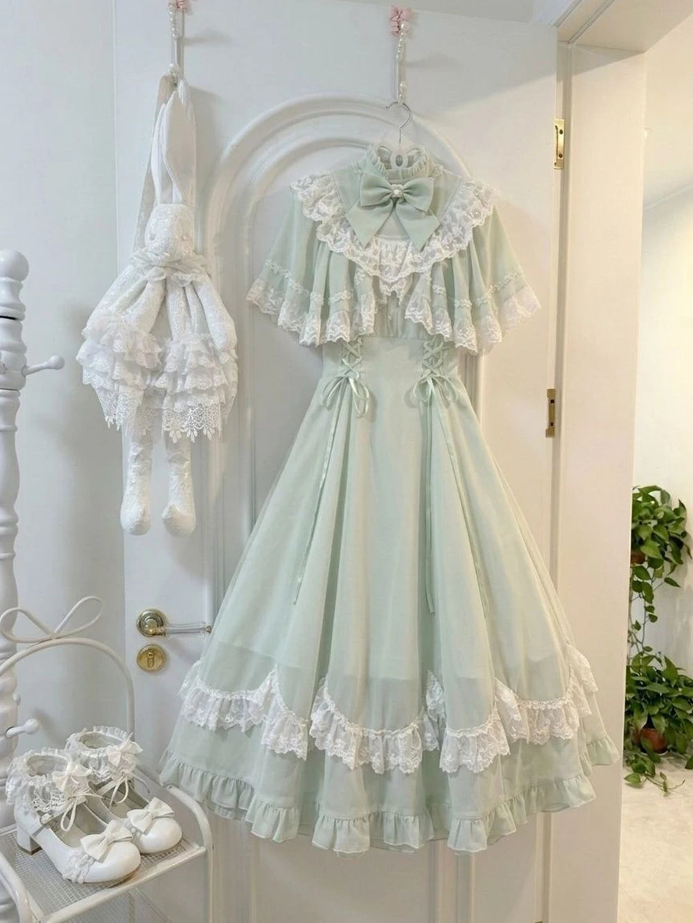 Green one-piece dress and lace cape hanging together
