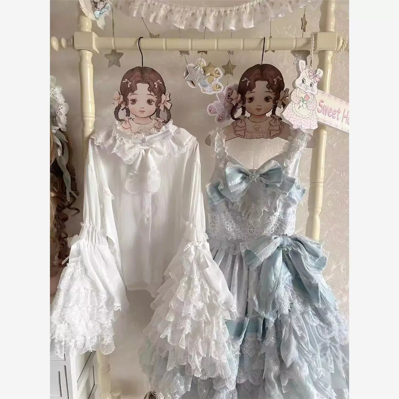 White chiffon blouse with a ruffled collar and wide lace cuffs hanging on display.