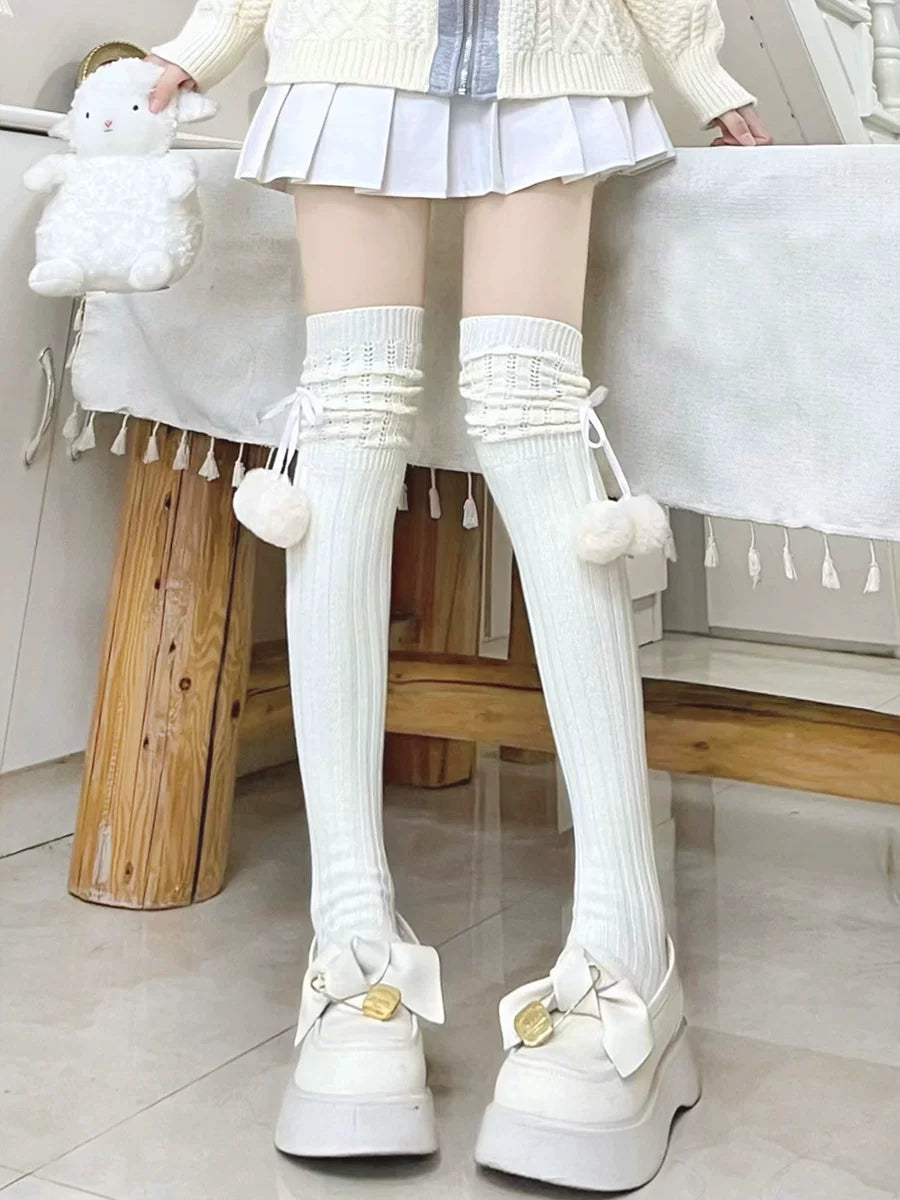 White ribbed thigh-high socks with side ribbons and pom-poms worn with platform shoes.