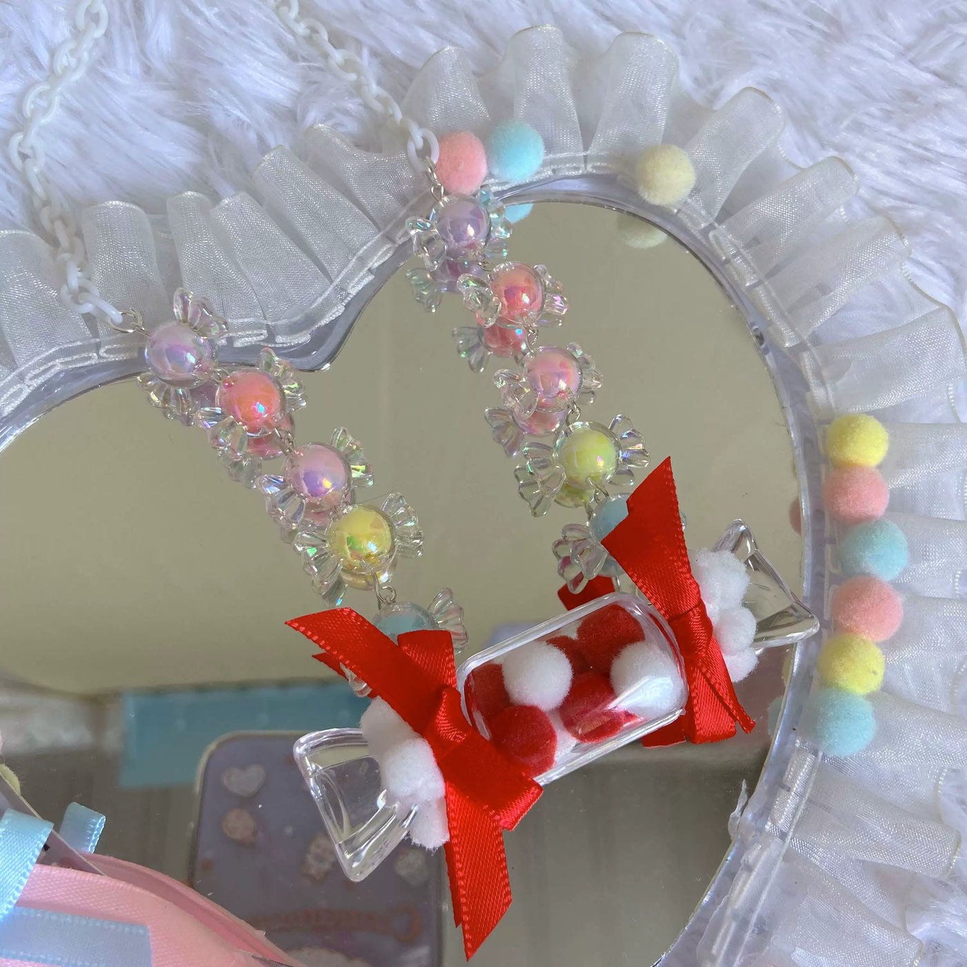 Colourful beaded necklaces with flower-like clusters, candy charms and ribbon bows arranged on a mirrored surface.