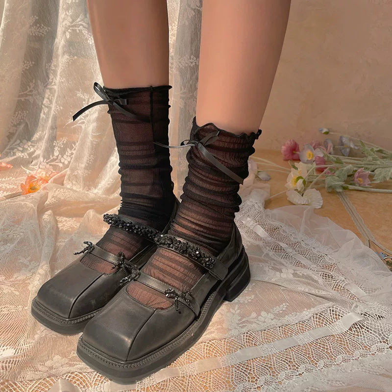 Black sheer mid-calf Lolita socks with frilled cuffs and bow accents