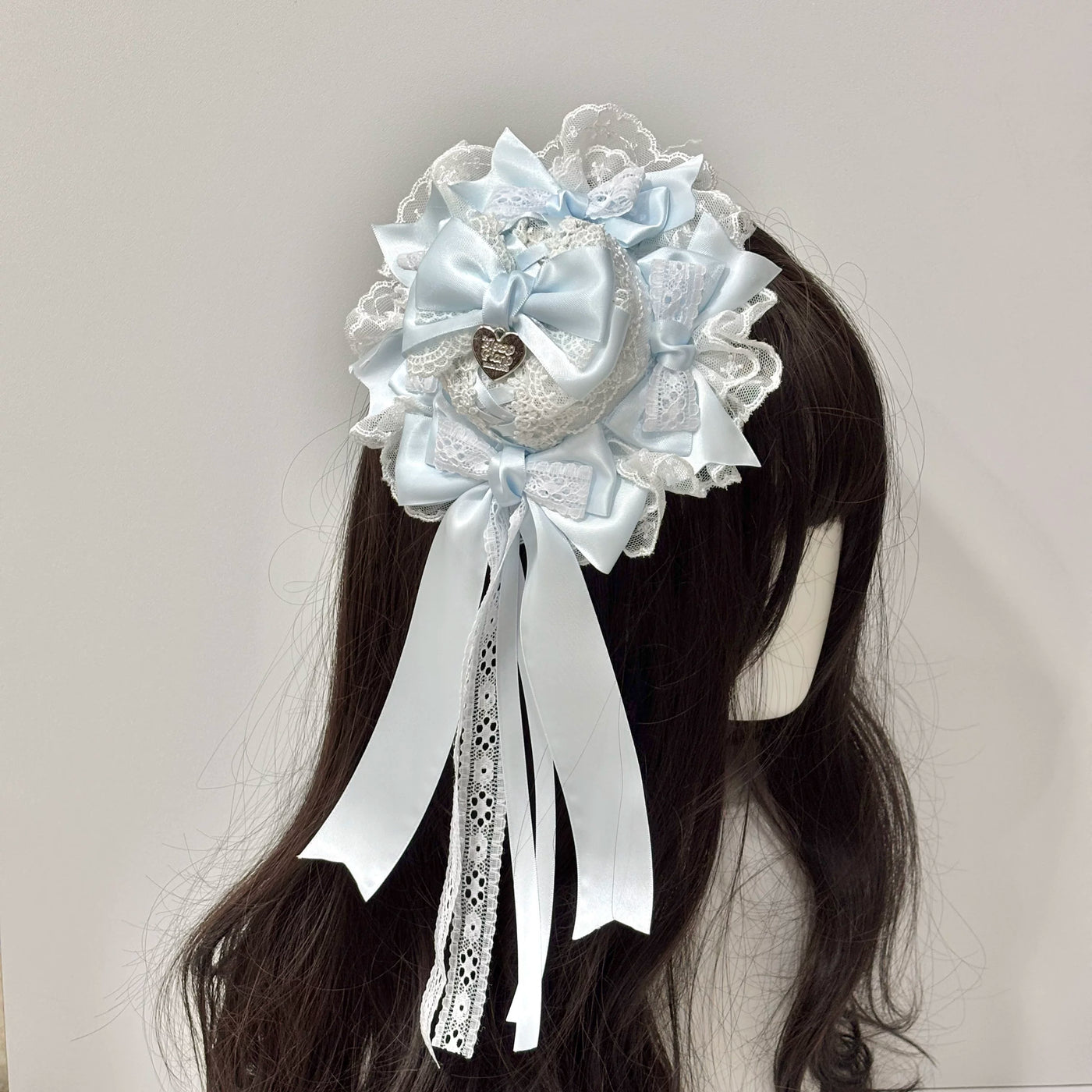 Light blue lace-and-bow mini top hat shown on a mannequin.