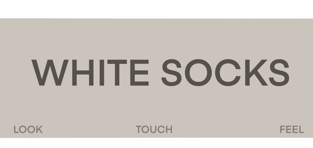 Grey slouch mid-calf socks with black letter prints worn with light sneakers.