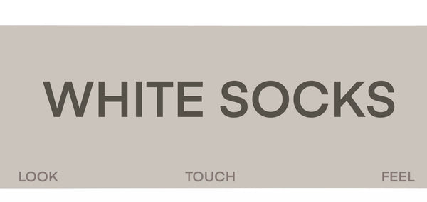 Grey slouch mid-calf socks with black letter prints worn with light sneakers.