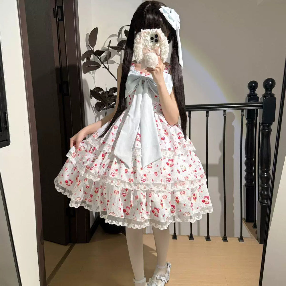 Pink printed three-tier JSK dress with a large bow and lace-edged ruffles shown in a mirror.