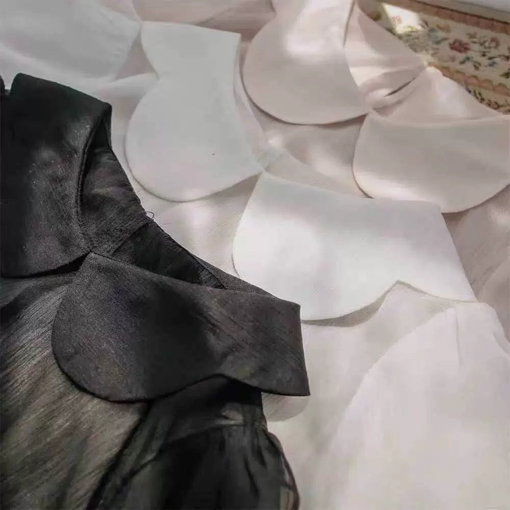 White lightweight pullover blouse with petal collar and gathered puff sleeves on a hanger
