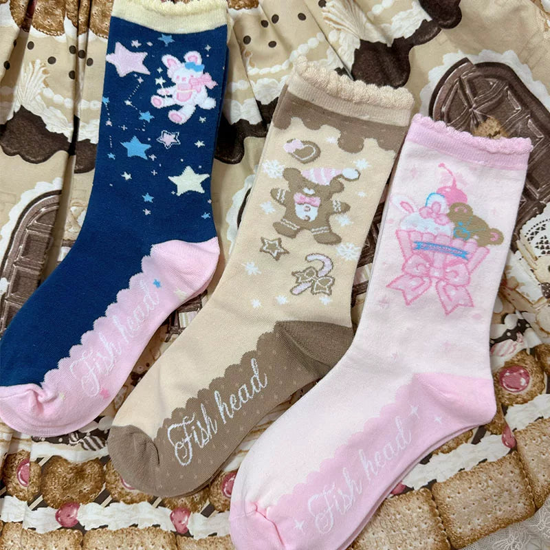 Three cartoon-print socks in navy, tan and pink designs shown in full.