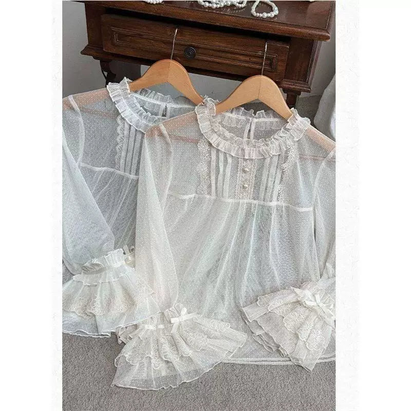 White lace inner blouses with ruffled collars and flared sleeves shown on hangers.
