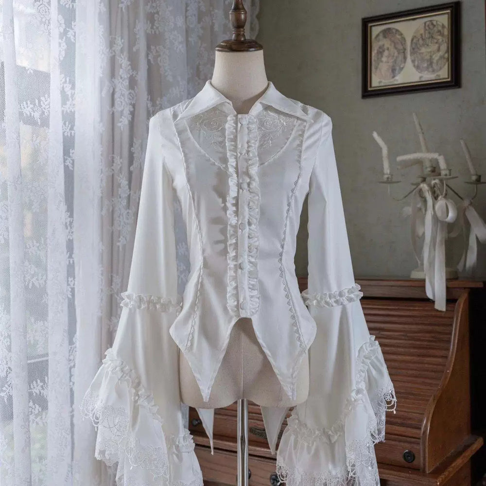 White and black long-sleeve blouses with pointed collars and dramatic lace-trimmed sleeves.