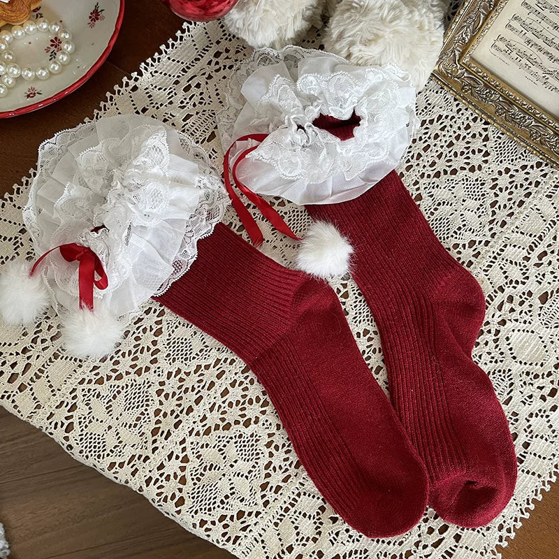 White ribbed slouch socks with lace ruffles, red ribbons, and white fur-ball accents