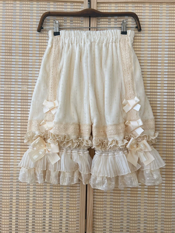 Creamy white Lolita bloomers with lace panels, bows and layered ruffle cuffs on a hanger