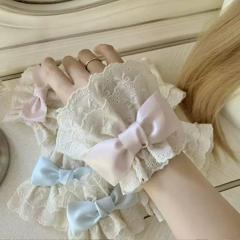 White lace sleeve cuffs with pink and blue bow accents shown on hands.