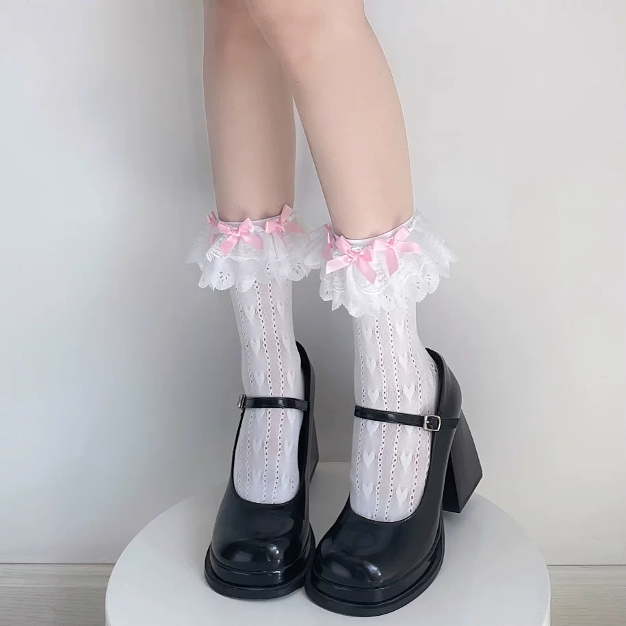 White lace-trimmed mid-calf socks with pink bows styled with black Mary Jane shoes