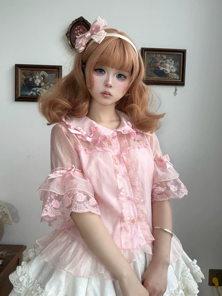 Model wearing a pink doll-collar blouse with lace-trimmed sleeves and a white skirt.