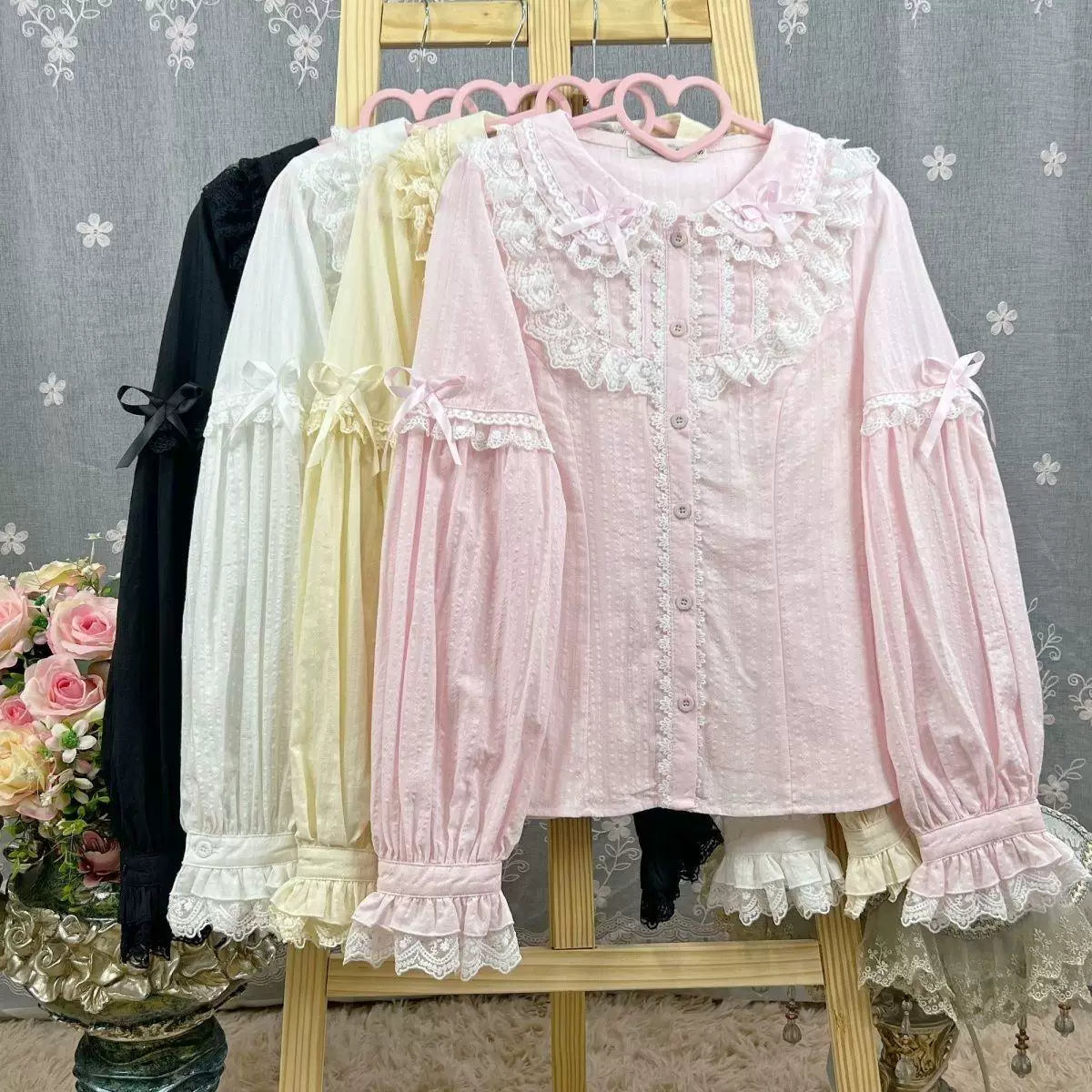 Sweetheart Dream Machine lace-collar blouses in pink, white and natural tones arranged on a rack.