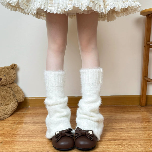 Model wearing white fluffy slouch leg warmers over brown Mary Jane-style shoes.