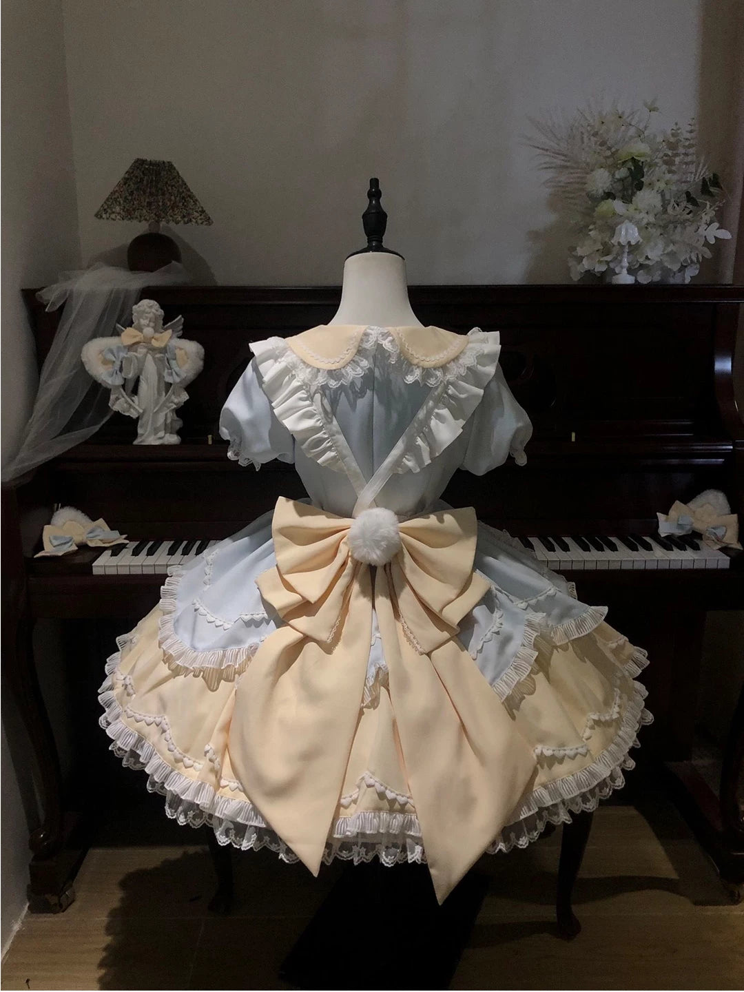 Blue-and-cream cat-motif OP dress set displayed on a mannequin in front of a piano.