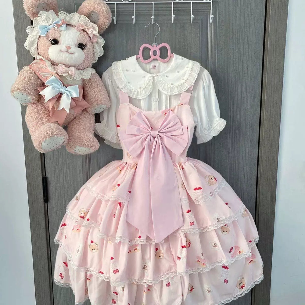 Black Lolita OP dress with large bow, white collar and tiered printed skirt shown on a model.